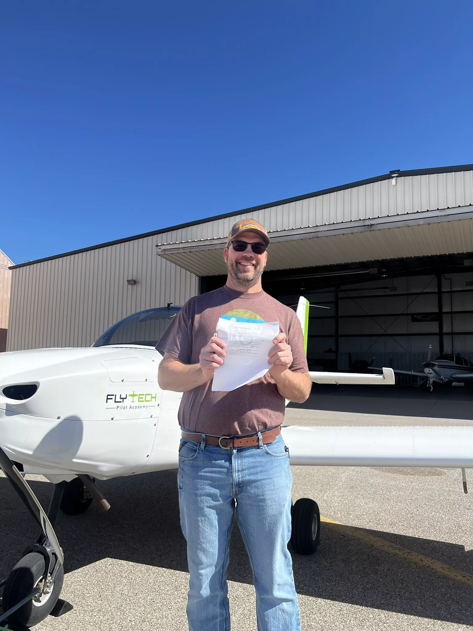 Proud student holding FAA pilot certificate after passing checkride